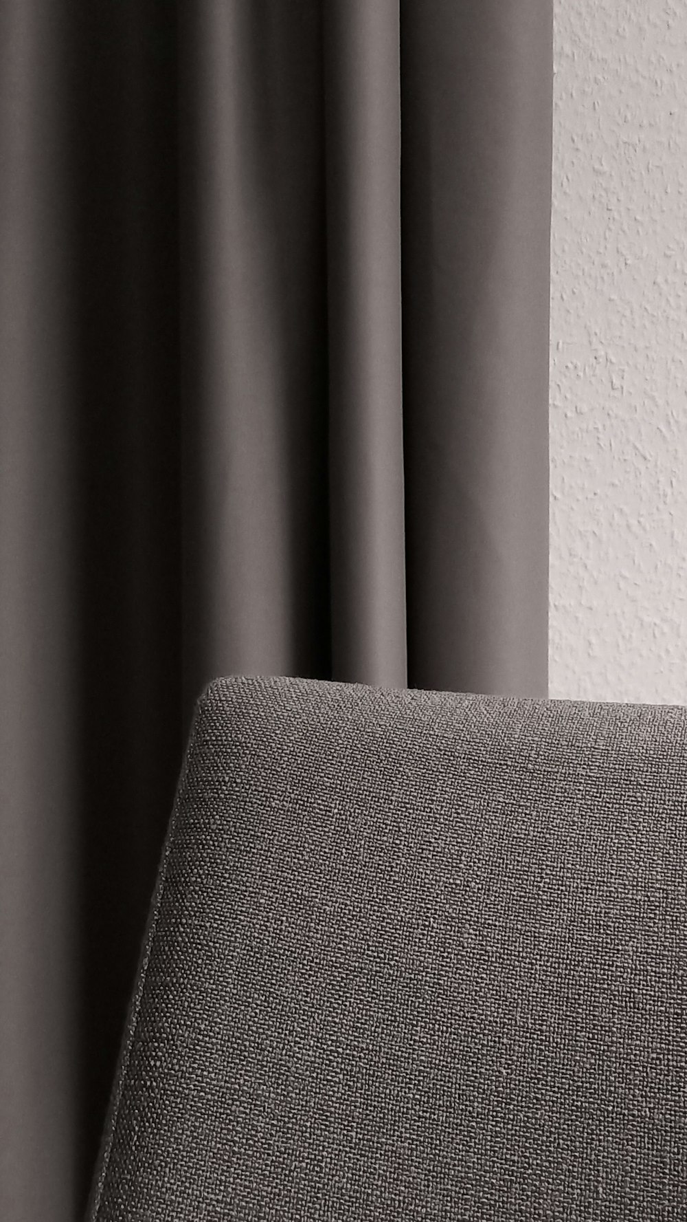 a close up of a gray couch with a white wall in the background