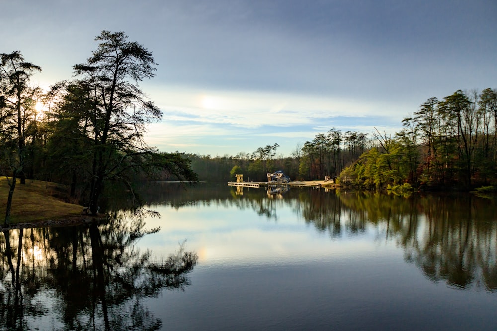 a body of water surrounded by trees under a cloudy sky