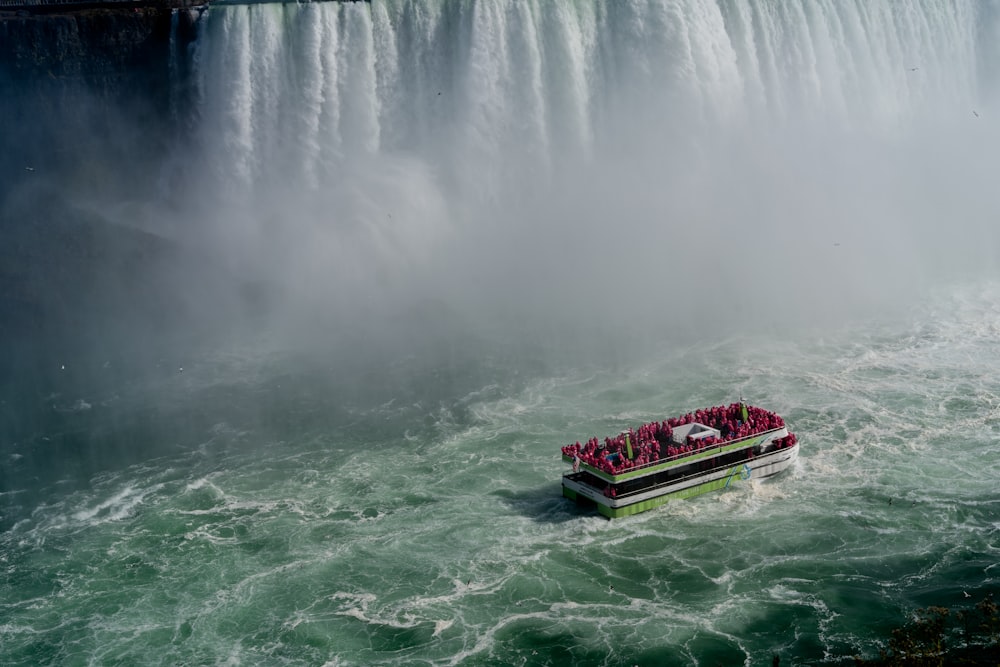 a boat filled with people in front of a waterfall