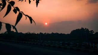 Sunset casting warm light over a completed section of road with clear markings and sturdy guardrails