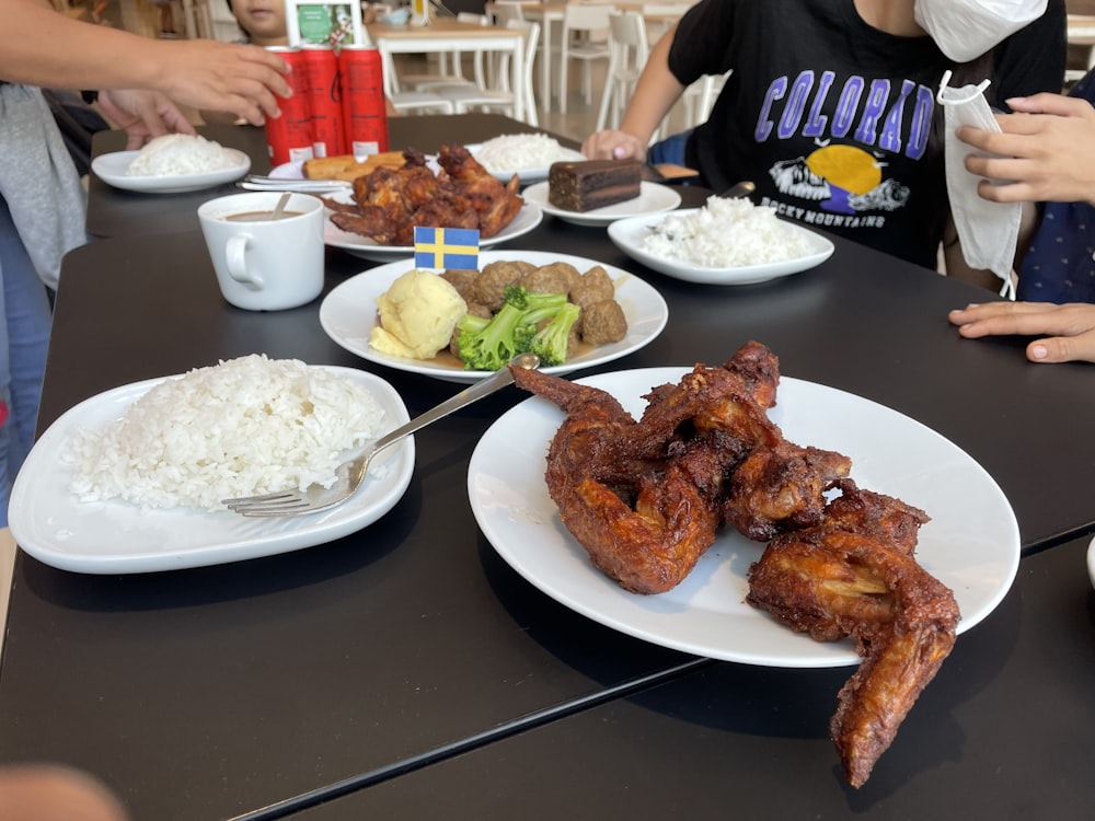 a group of people sitting at a table with plates of food