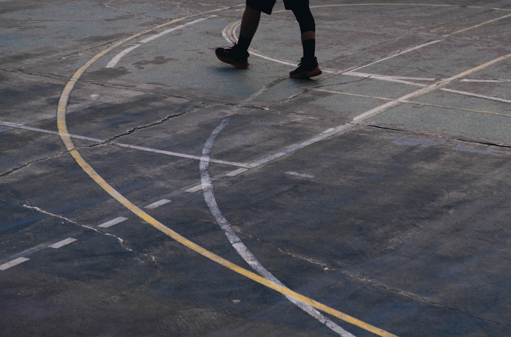a person walking across a basketball court holding a basketball