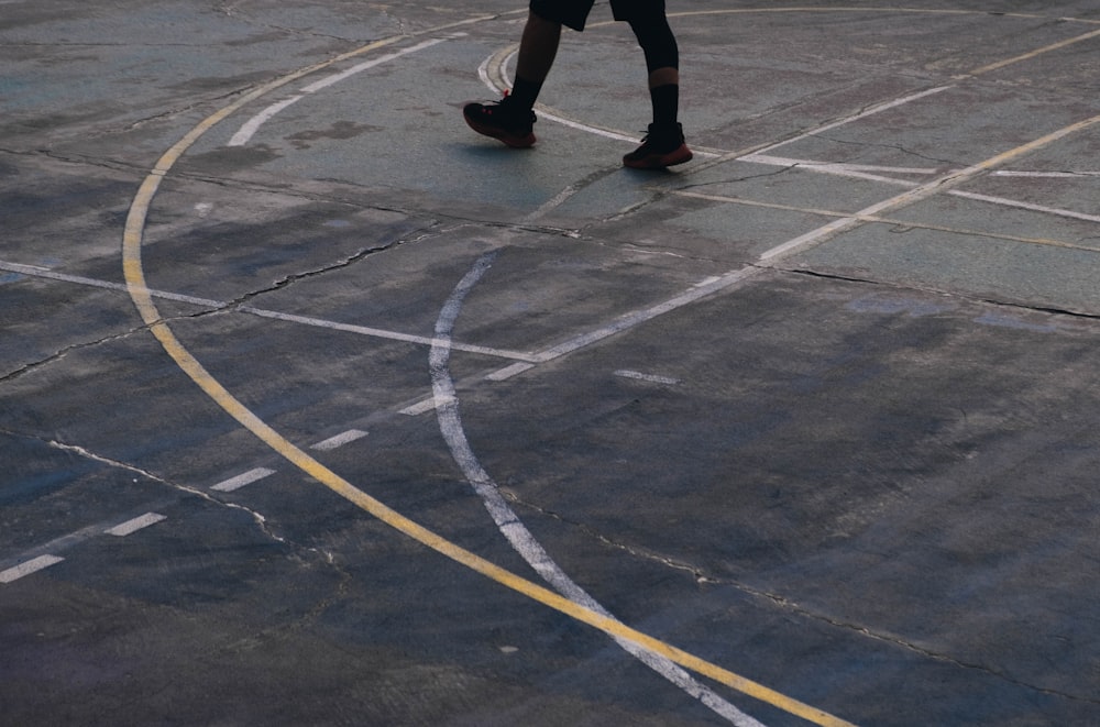 Una persona caminando por una cancha de baloncesto sosteniendo una pelota de baloncesto