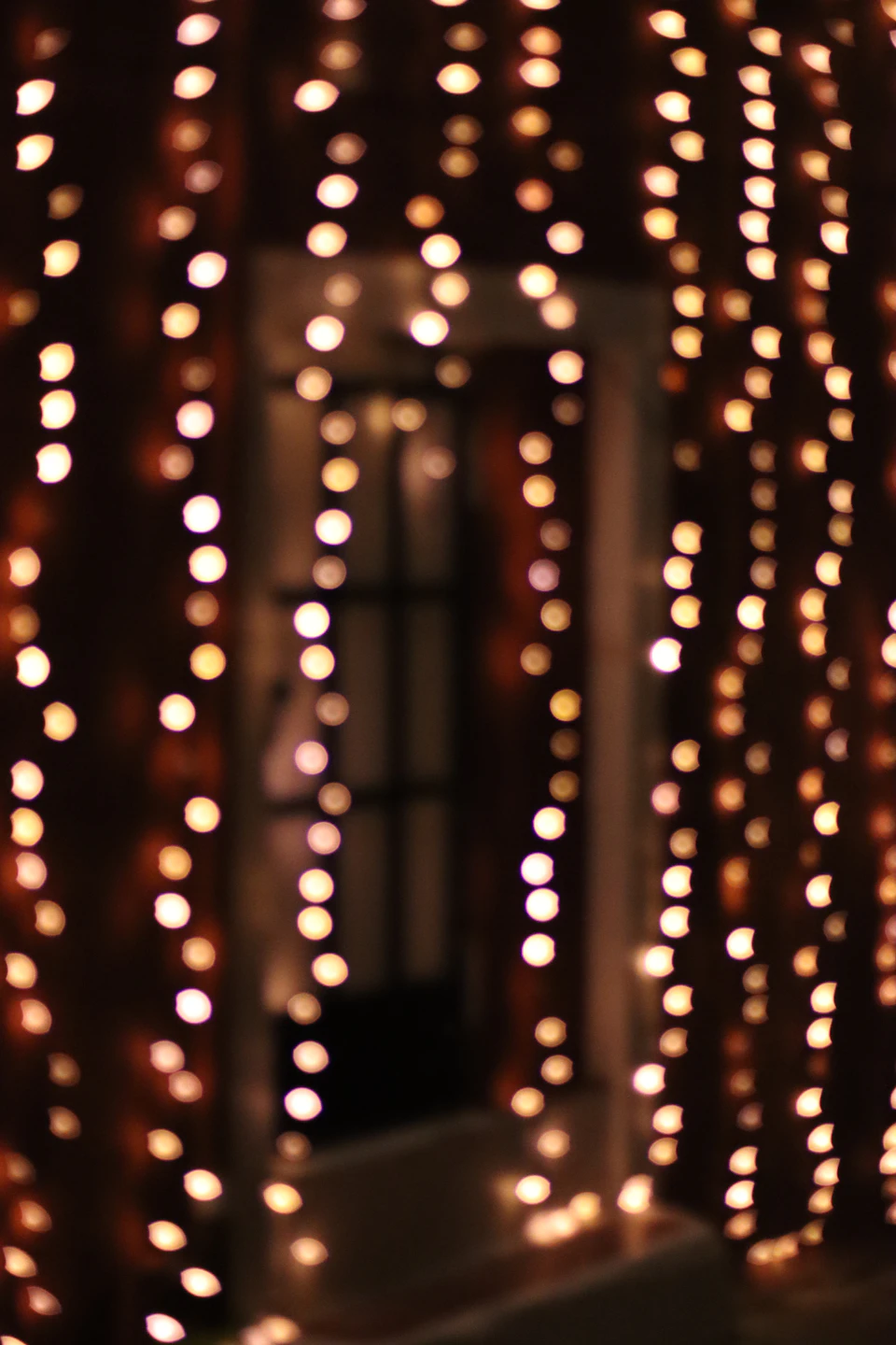 Large window with numerous small round lights arranged in a zigzag pattern on wall