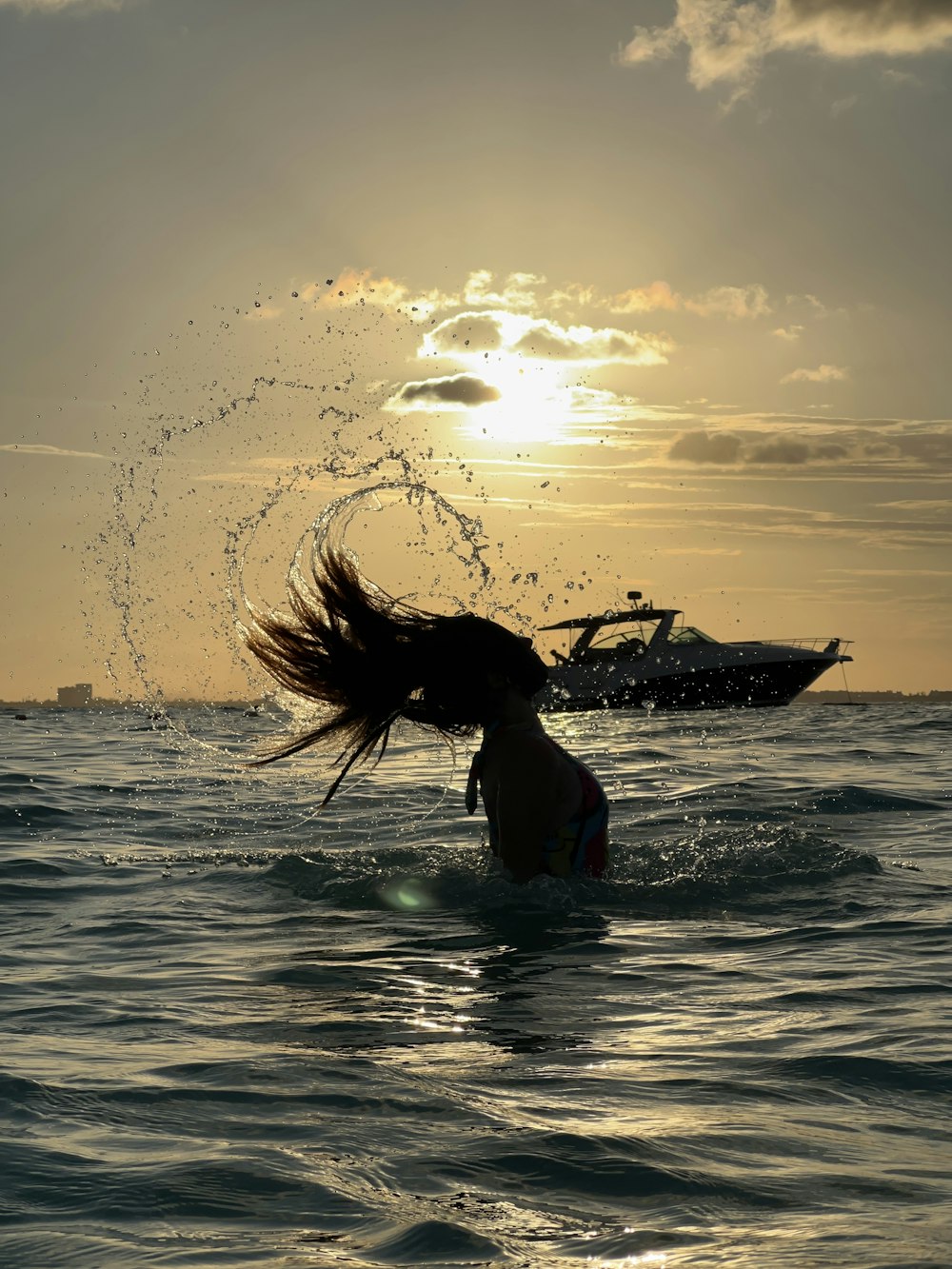 a woman standing in the ocean with her hair blowing in the wind