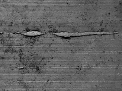 A grainy, monochrome image of layered textures resembling worn paper.