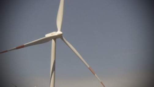A wind farm with several turbines against a clear blue sky.