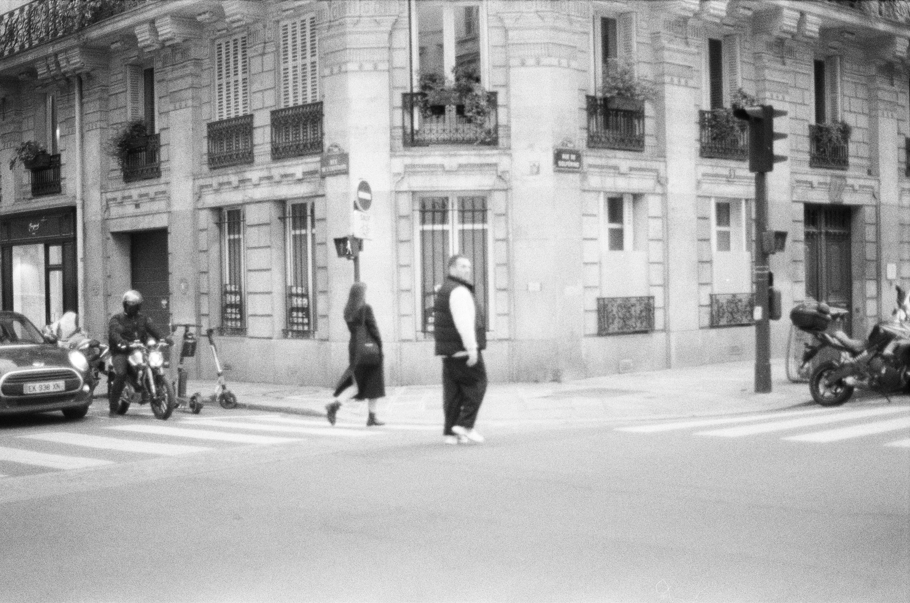 a black and white photo of people crossing the street