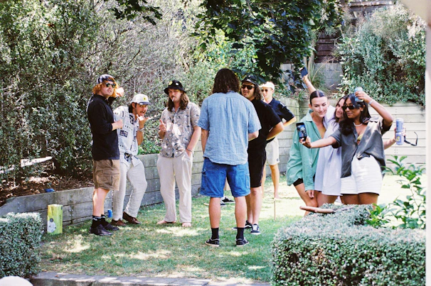 A gentle sunlit garden scene with guests dressed in light, elegant attire mingling happily.
