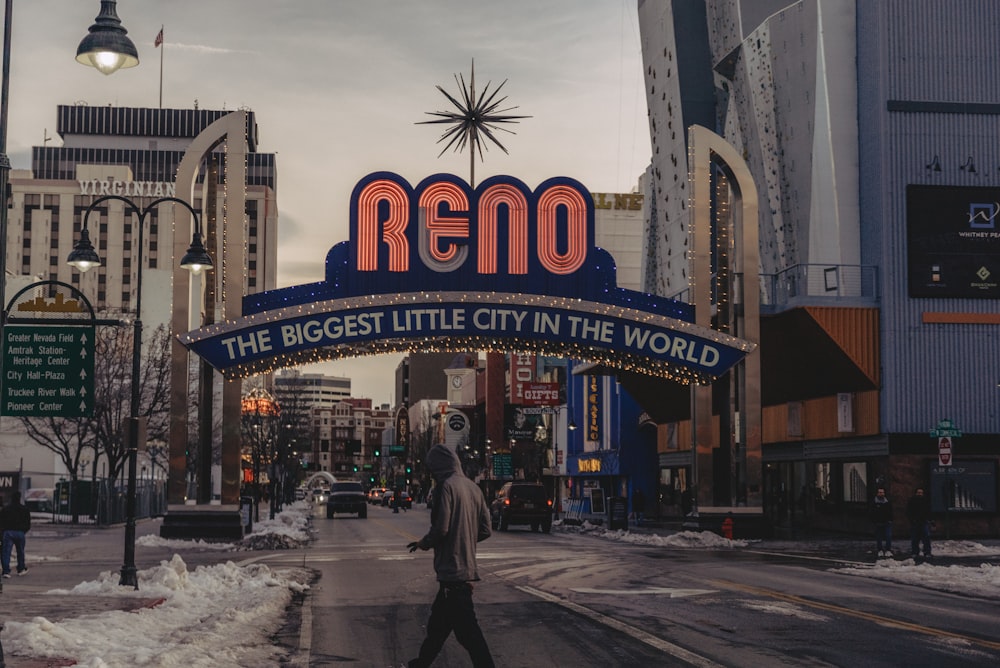 a man walking down a street under a neon sign