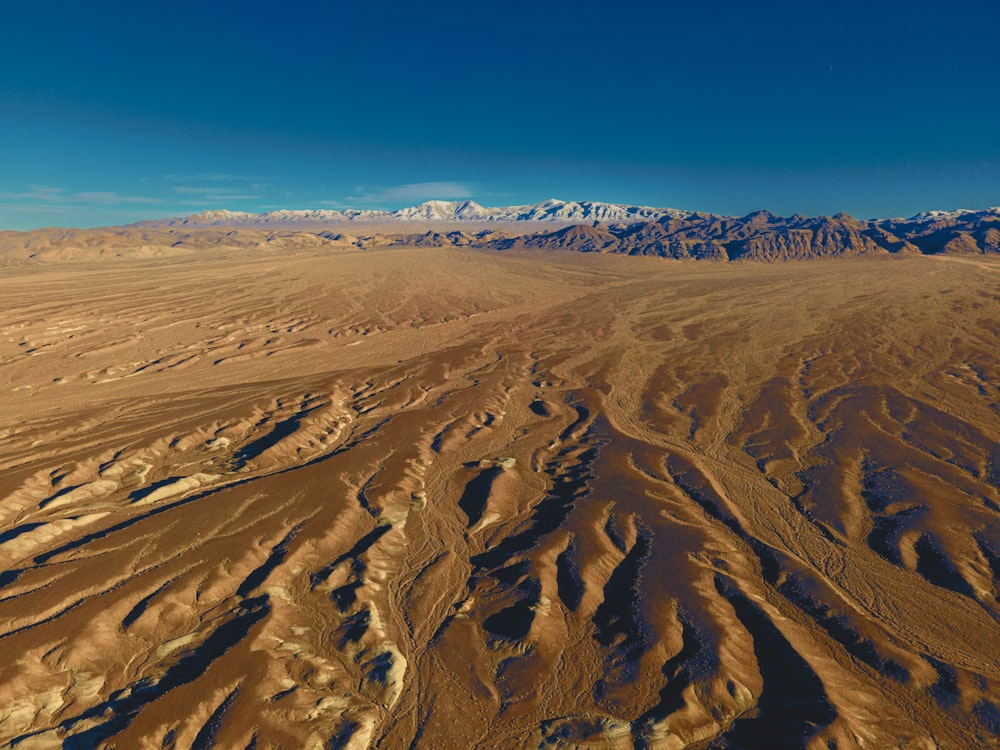 an aerial view of a desert with mountains in the background