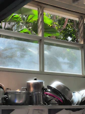 Close-up of shiny stainless steel pots and pans neatly arranged on a wooden kitchen shelf.