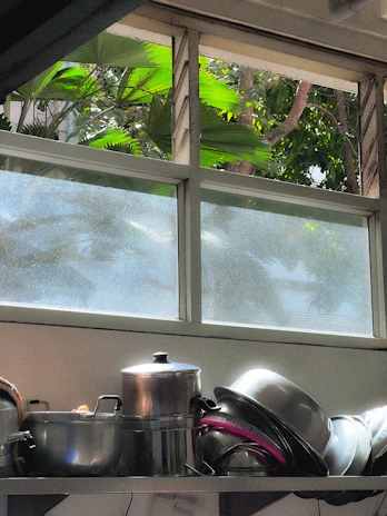 Close-up of shiny stainless steel pots and pans neatly arranged on a wooden kitchen shelf.