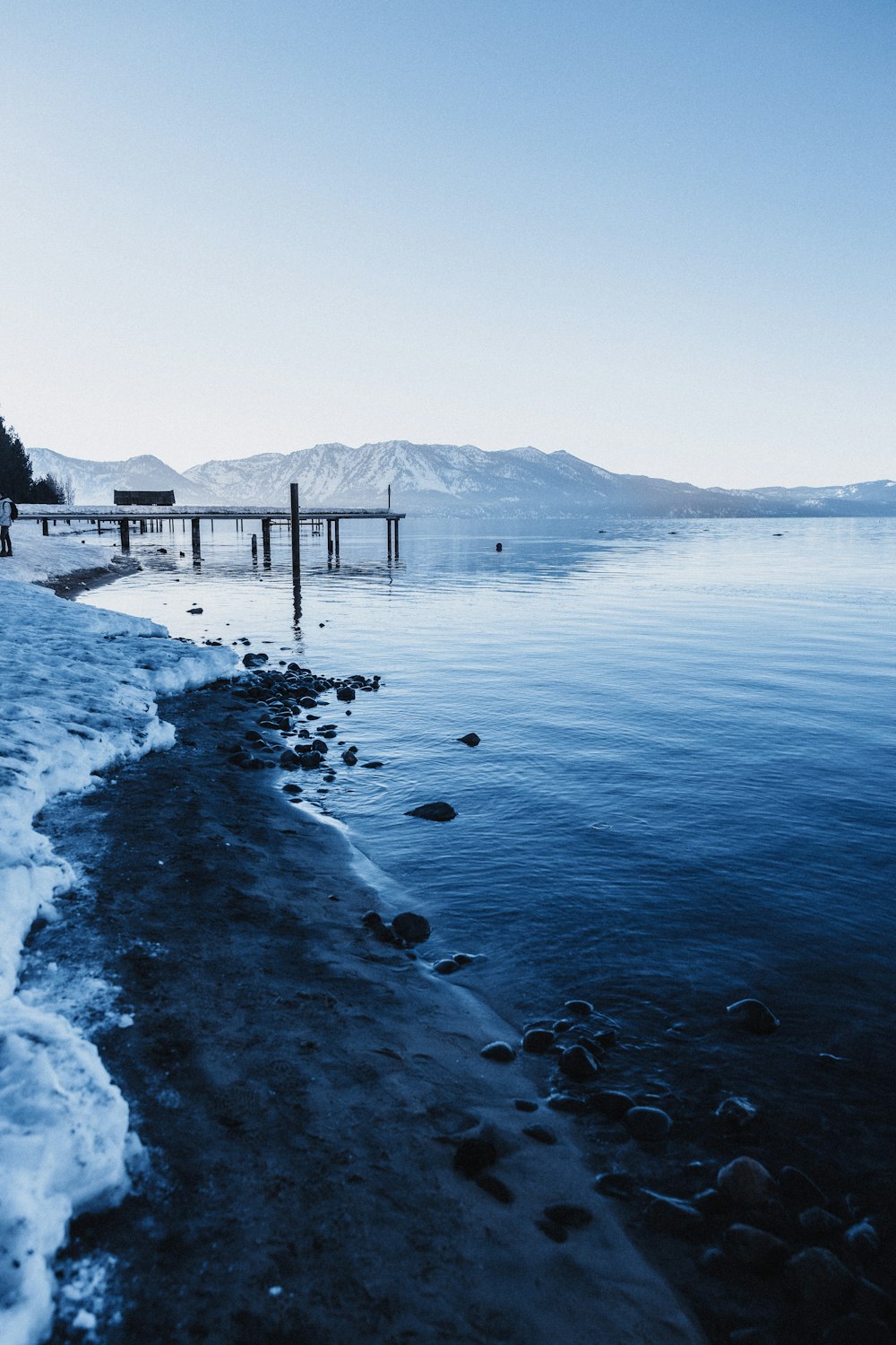 a body of water surrounded by snow covered mountains