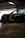 A sleek, modified sports car with exposed engine components is parked inside a garage. The vehicle has a dark exterior with visible aerodynamic elements, such as a significant body kit. Parts of the hood are removed, revealing intricately designed metal pipes and components.