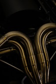 A close-up view of metallic pipes with a smooth, curved design. The pipes appear to be made of polished metal, reflecting light and showcasing a shiny surface.
