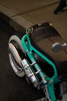 A rugged biker adjusting the handlebars on a freshly painted chopper with metallic finishes.