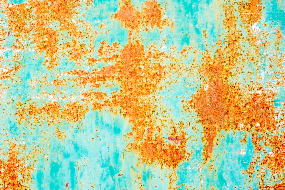 a rusted metal surface with blue and orange paint