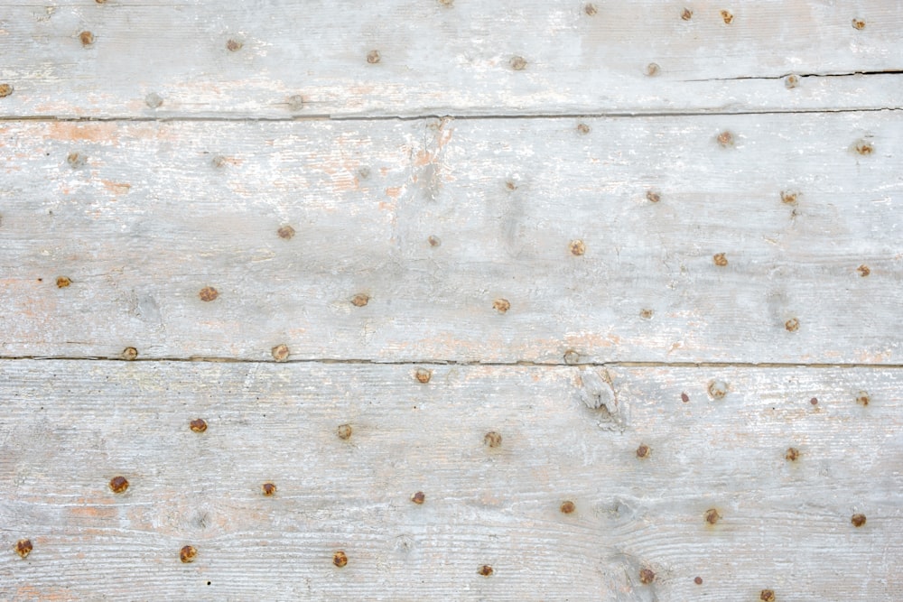 a white wooden surface with rivets and nails