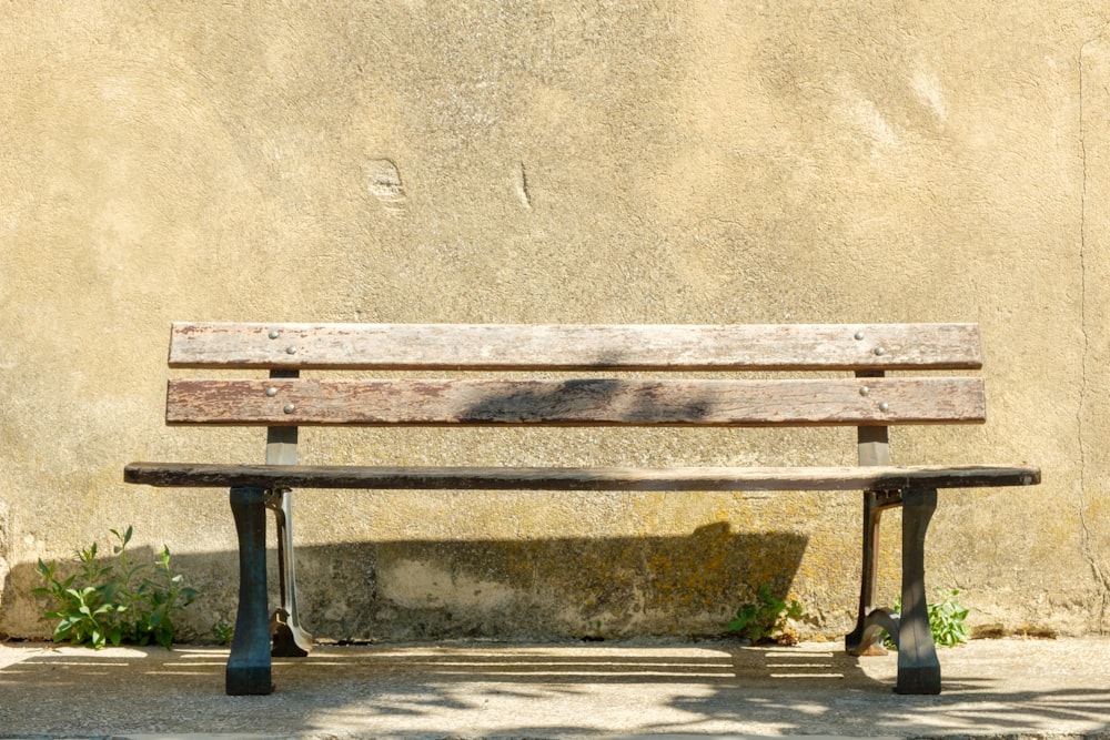 a wooden bench sitting in front of a wall