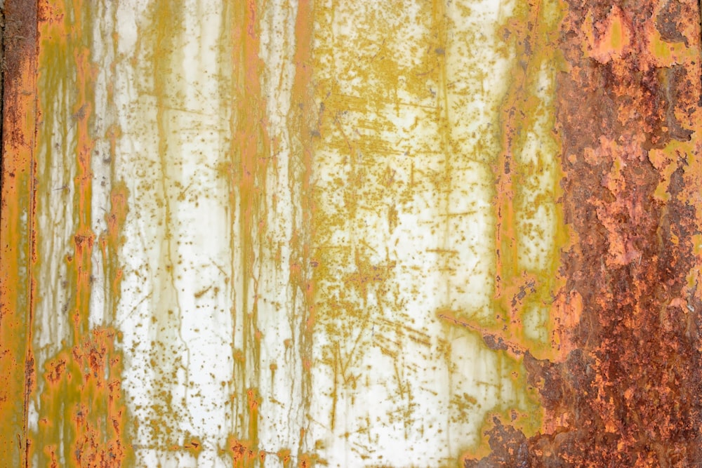 a rusted metal surface with yellow and orange streaks