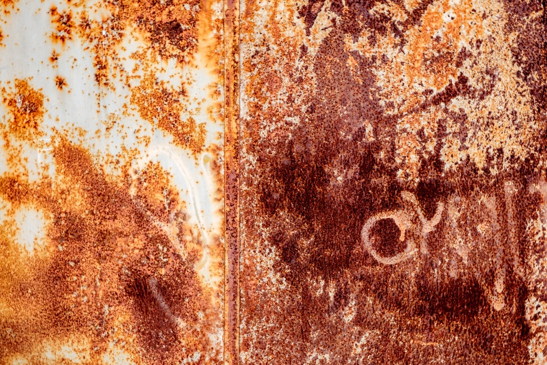 a rusted metal surface with some writing on it,