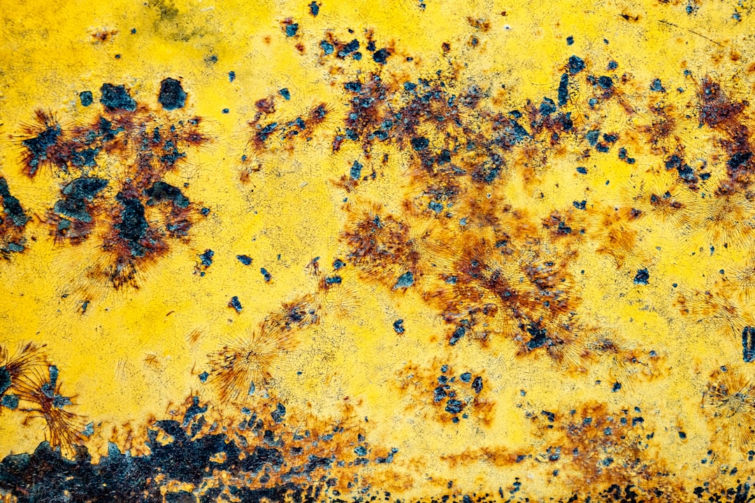 a yellow and black wall with lots of rust on it,
