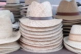 An overhead shot of several handcrafted straw hats arranged in a circle on a light linen cloth.
