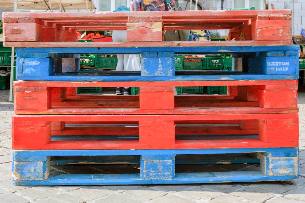 a stack of red and blue crates sitting on top of a sidewalk