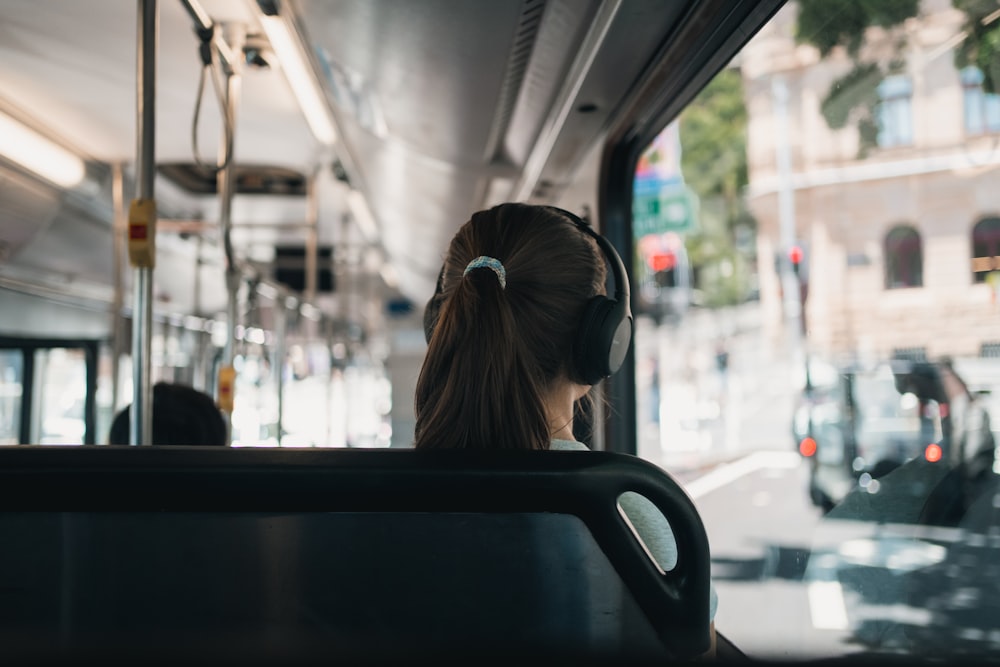 a woman with headphones sitting on a bus