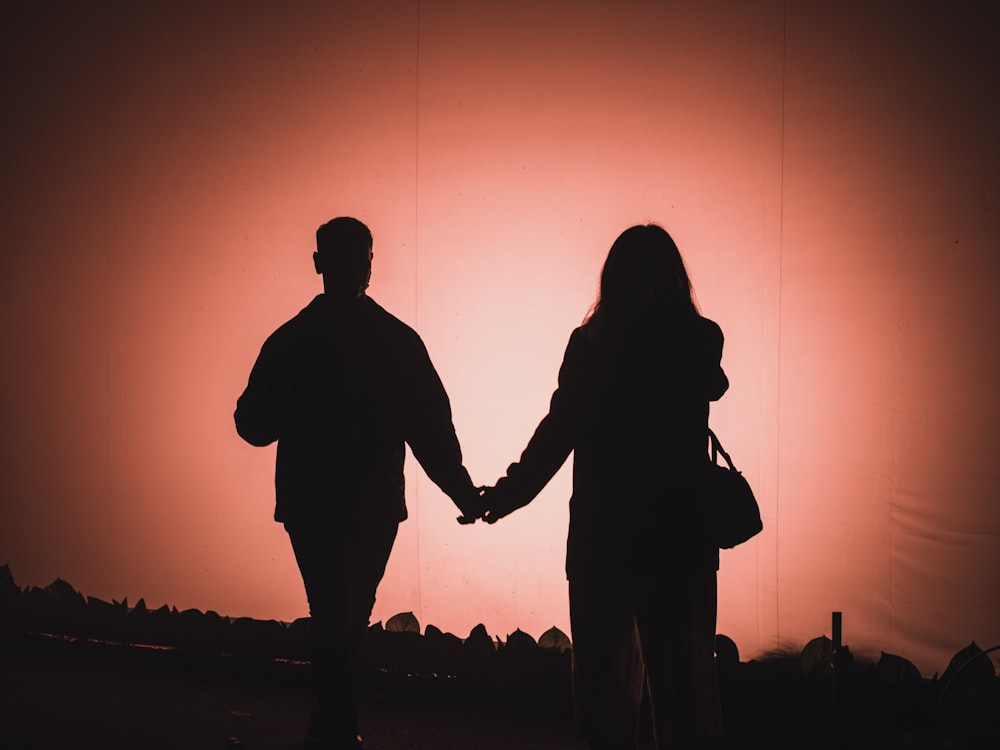 a man and a woman hold hands as the sun sets