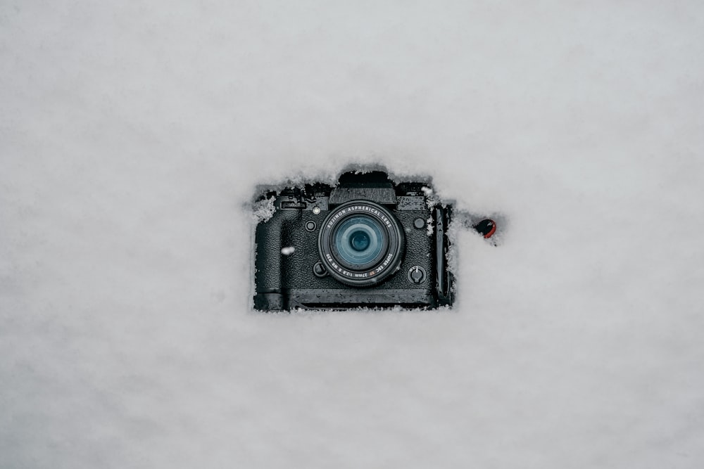 a camera sitting in the snow with a blue lens