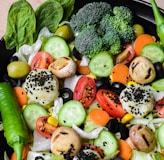 a black bowl filled with vegetables on top of a wooden table