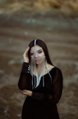 A moody, editorial-style shot of a model wearing multiple micro-welded chains around her neck, set against a deep forest green backdrop.