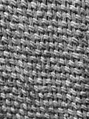 A close-up view of a woven textile, highlighting the texture and pattern of interlaced fibers. The image showcases the intricate details of the weave, emphasizing the individual strands and the way they are intertwined.