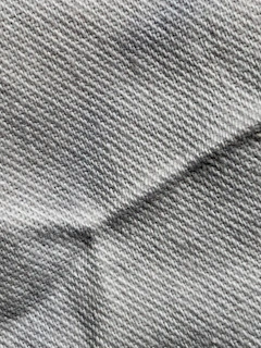 Close-up of cool slate gray knit fabric draped elegantly over a clean white background.