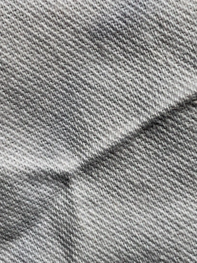 Close-up of cool slate gray knit fabric draped elegantly over a clean white background.