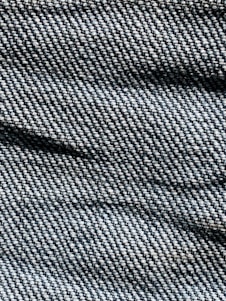 A close-up view of denim fabric with visible texture, showing the intricate weave pattern and shades of blue and white threads.