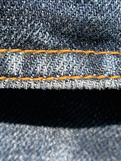Close-up of durable industrial uniform fabric with orange accents under bright lighting