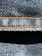 Close-up view of denim fabric highlighting the texture of the woven material. The stitching is a prominent feature, showing a line of neat orange thread running across the fabric.