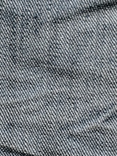 A close-up view of denim fabric with visible blue and white threads intersecting to form a classic twill pattern.