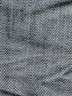 A close-up view of denim fabric with visible blue and white threads intersecting to form a classic twill pattern.
