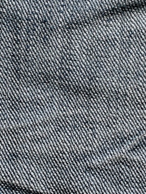 A close-up view of denim fabric with visible blue and white threads intersecting to form a classic twill pattern.