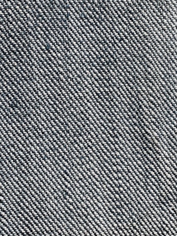 A close-up view of a woven fabric texture featuring a dense pattern of interlaced threads. The fabric appears sturdy and thick, with a prominent diagonal weave pattern, indicative of denim material.