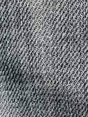 A close-up view of textured denim fabric with a detailed, diagonal weave pattern in shades of blue and white.