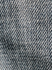 A close-up view of textured denim fabric with a detailed, diagonal weave pattern in shades of blue and white.