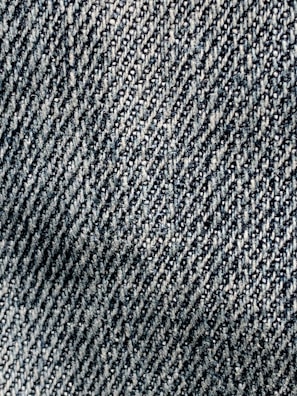 A close-up view of textured denim fabric with a detailed, diagonal weave pattern in shades of blue and white.