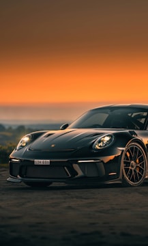 A sleek black sports car with a glossy custom paint finish reflecting the Dubai skyline at sunset.