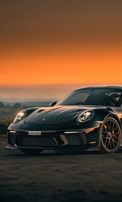 A sleek black sports car with a glossy carbon fiber spoiler catching the sunset light.