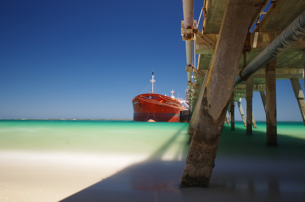 a red boat is docked at a pier